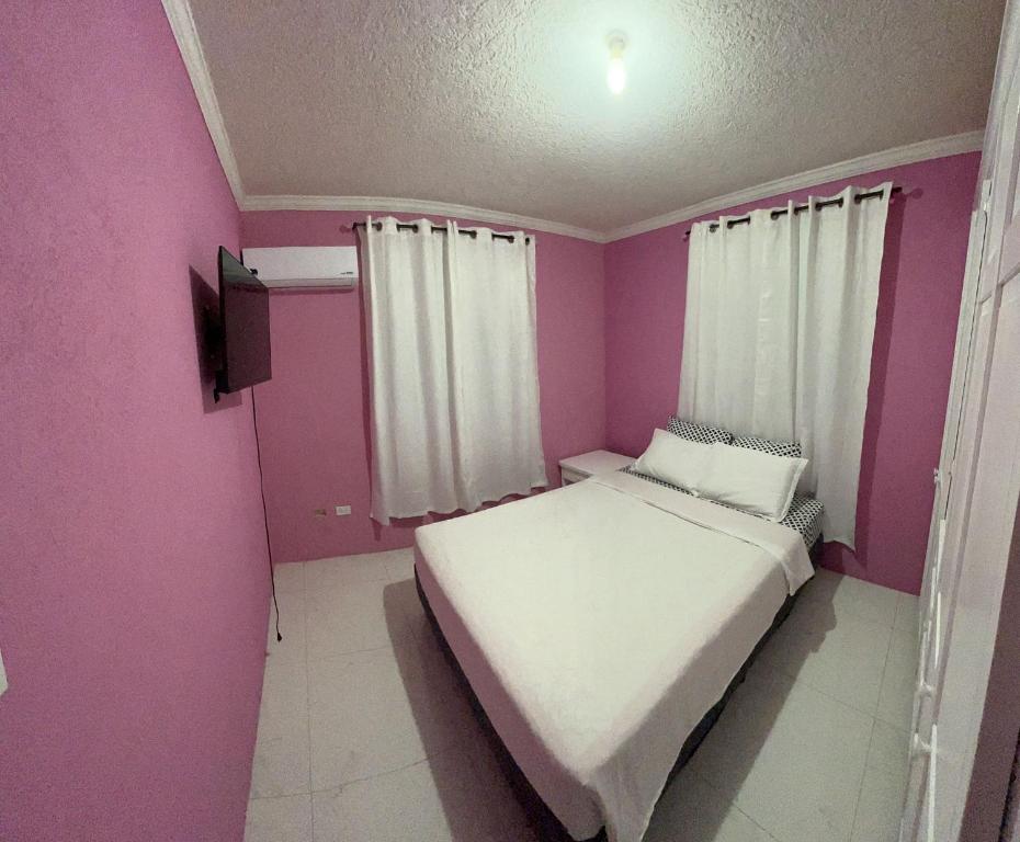 a small bedroom with a white bed and pink walls at Home away from home in Christ Church