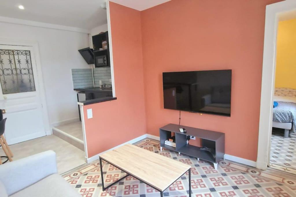 un salon avec une grande télévision à écran plat sur un mur dans l'établissement Cosy appartement 4 personnes aux Arceaux - Proche centre ville Montpellier, à Montpellier