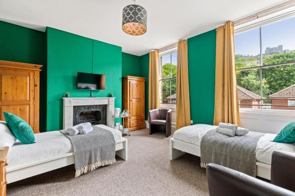 a green room with two beds and a fireplace at Dover Town Rooms - Short Lets & Serviced Accommodation - Dover in Dover
