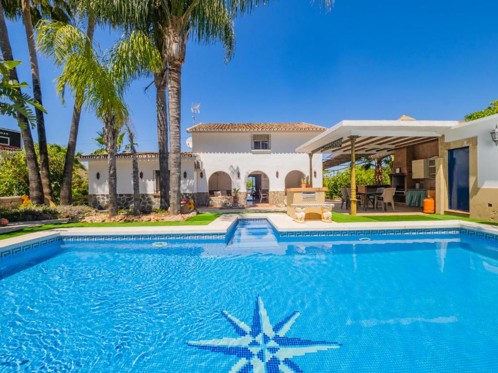 a swimming pool in front of a house with palm trees at Cubo's Finca Vallehermoso in Alhaurín el Grande