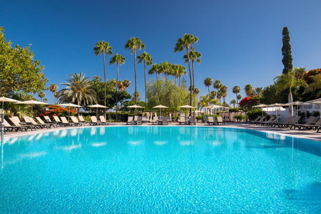 una gran piscina con sillas y sombrillas en Barceló Margaritas Royal Level Adults Only, en Playa del Inglés