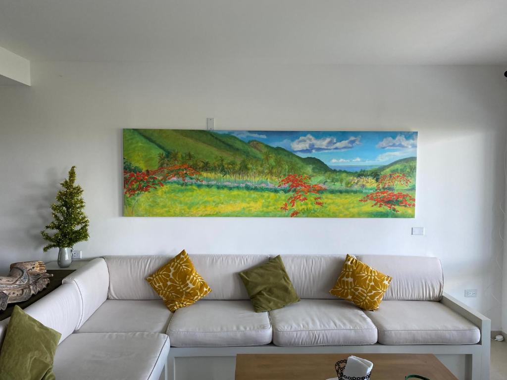 een woonkamer met een witte bank en een schilderij aan de muur bij Stunning 2 bedroom View condo in Maho in Lowlands