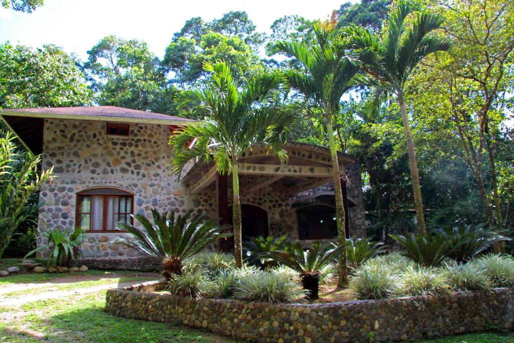 a stone house with palm trees in front of it at Casa Cangrejal B&B Hotel in La Ceiba