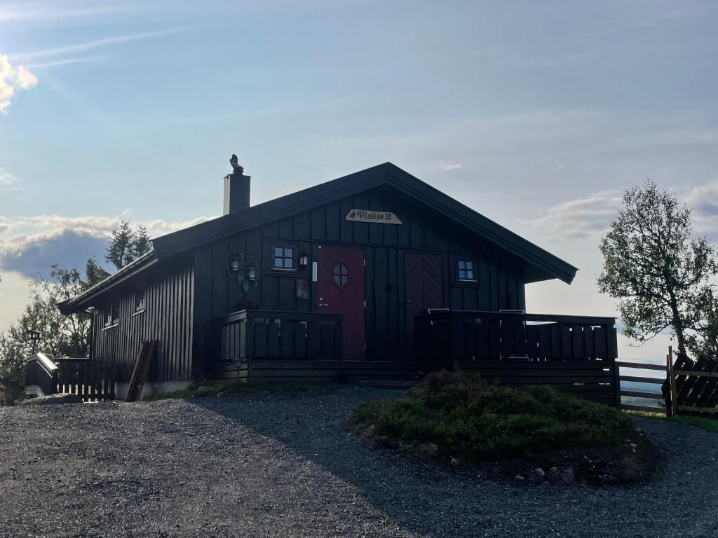 um grande celeiro de madeira com uma porta vermelha em Hytte med Anneks og fantastisk utsikt på Ljøsheim em Mesnali