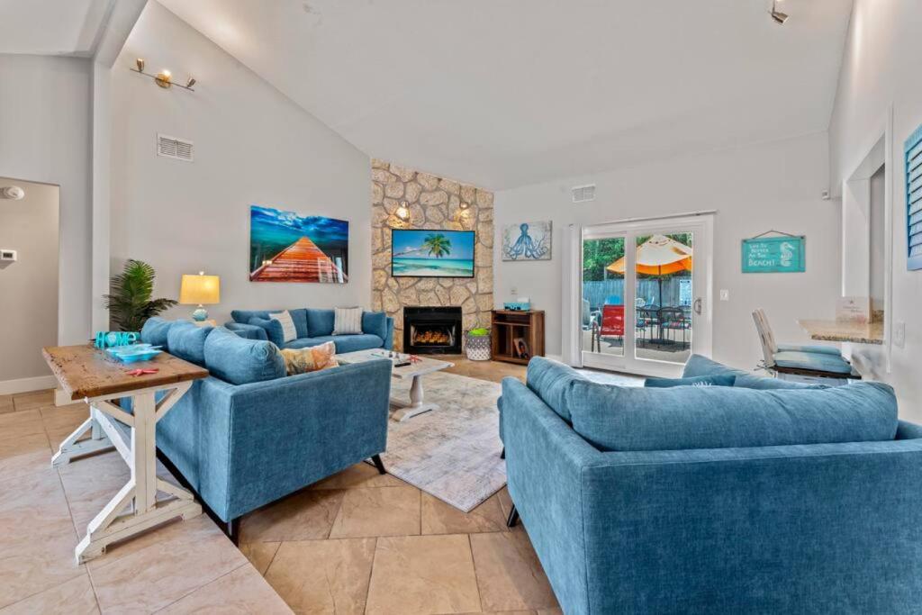 a living room with two blue couches and a fireplace at Saltwater Oasis - Large Pool in Jacksonville Beach
