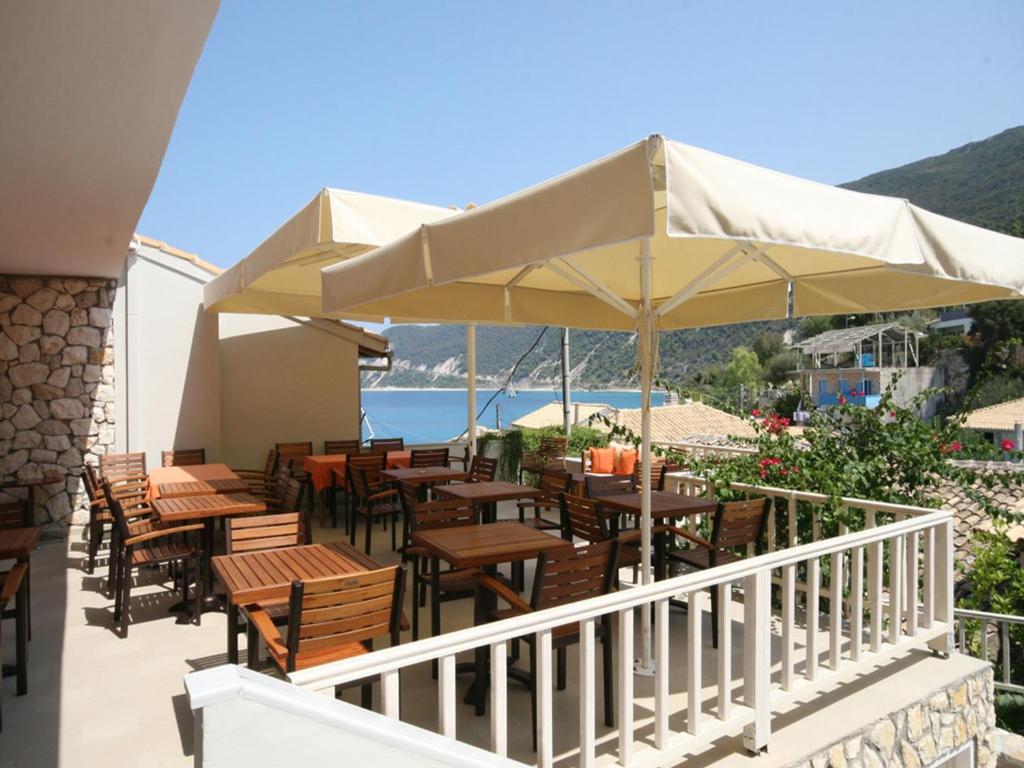 a patio with tables and chairs and an umbrella at Ionis Hotel in Agios Nikitas