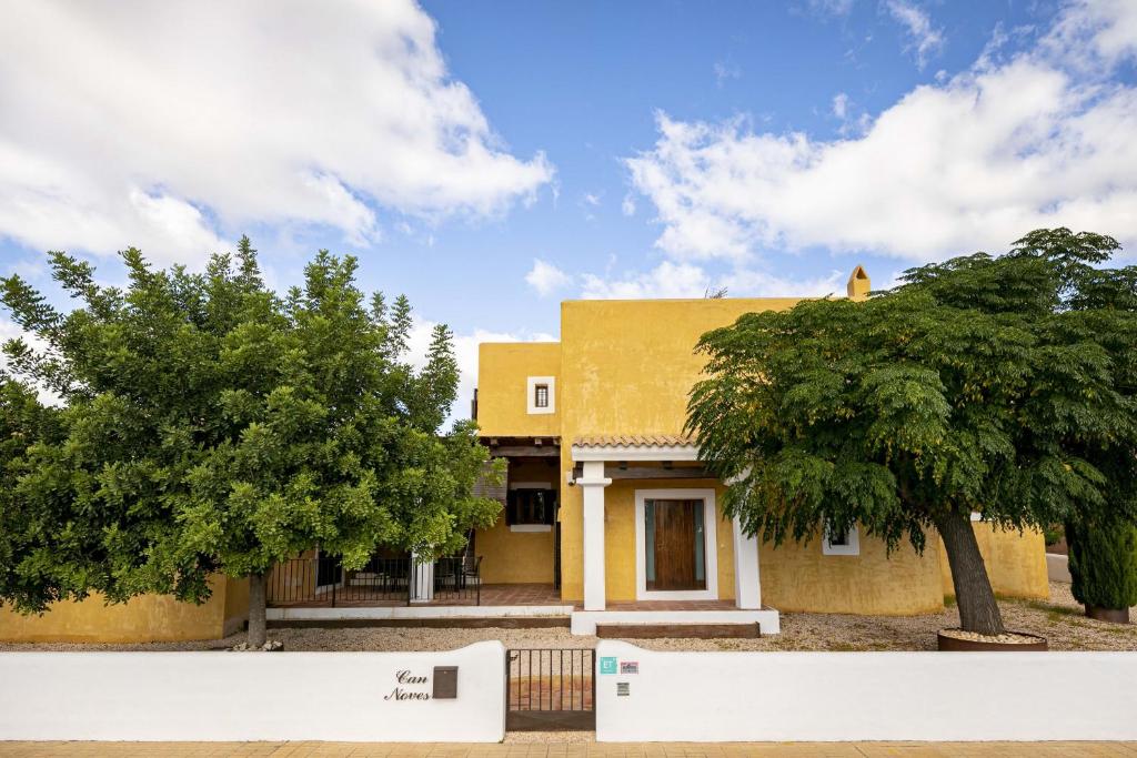 una casa amarilla con dos árboles delante de ella en CAN NOVES - Villa de 5 suites 31 y 9 en Sant Francesc Xavier