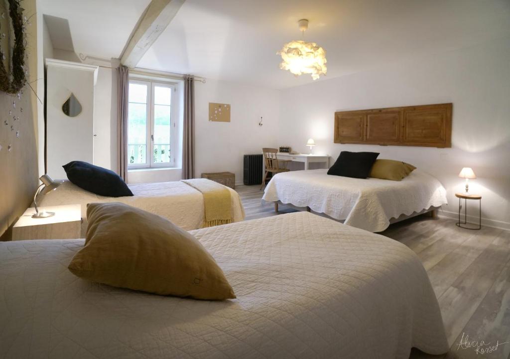 pokój hotelowy z 2 łóżkami i stołem w obiekcie Les Tilleuls w mieście Saint-Jean-dÊ¼Avelanne