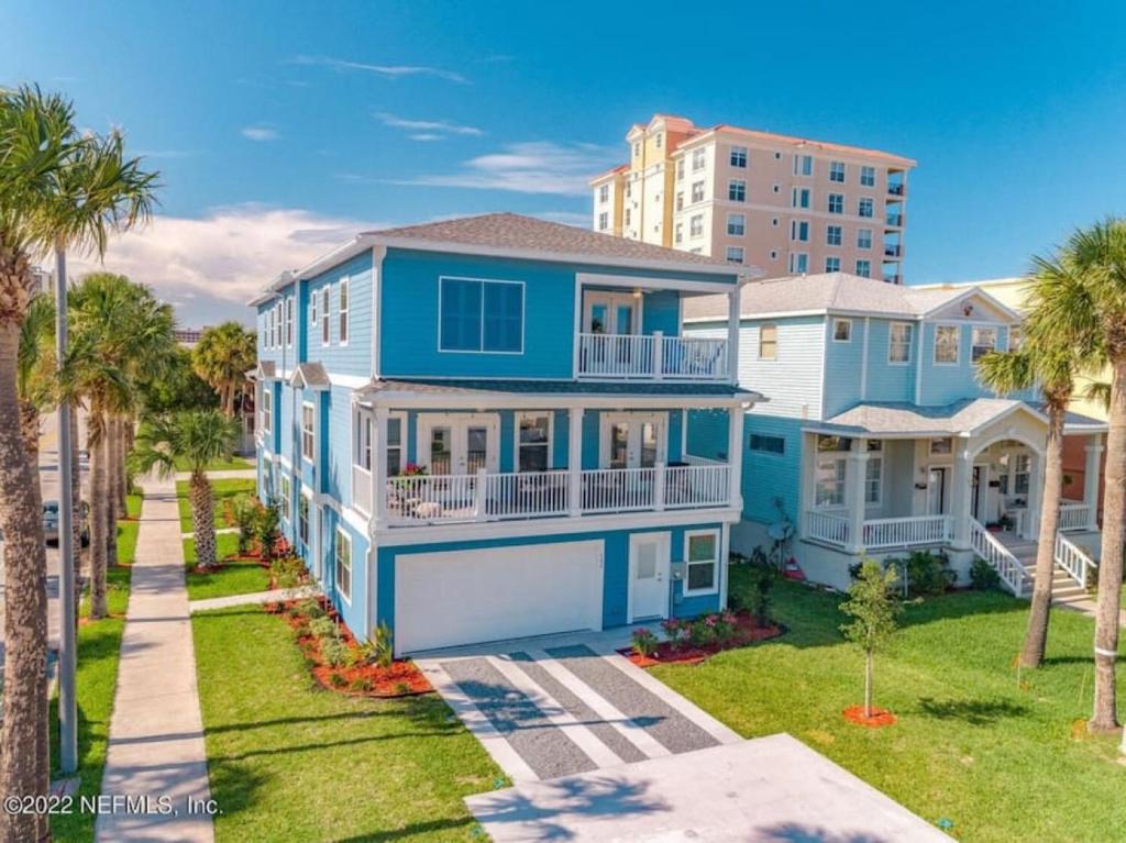 ein großes blaues Haus mit Palmen und einem Gebäude in der Unterkunft Ocean views, Elevator, Game Room, Two balconies in Jacksonville Beach