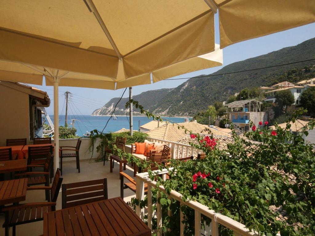 a patio with tables and chairs and a view of the ocean at Ionis Hotel in Agios Nikitas