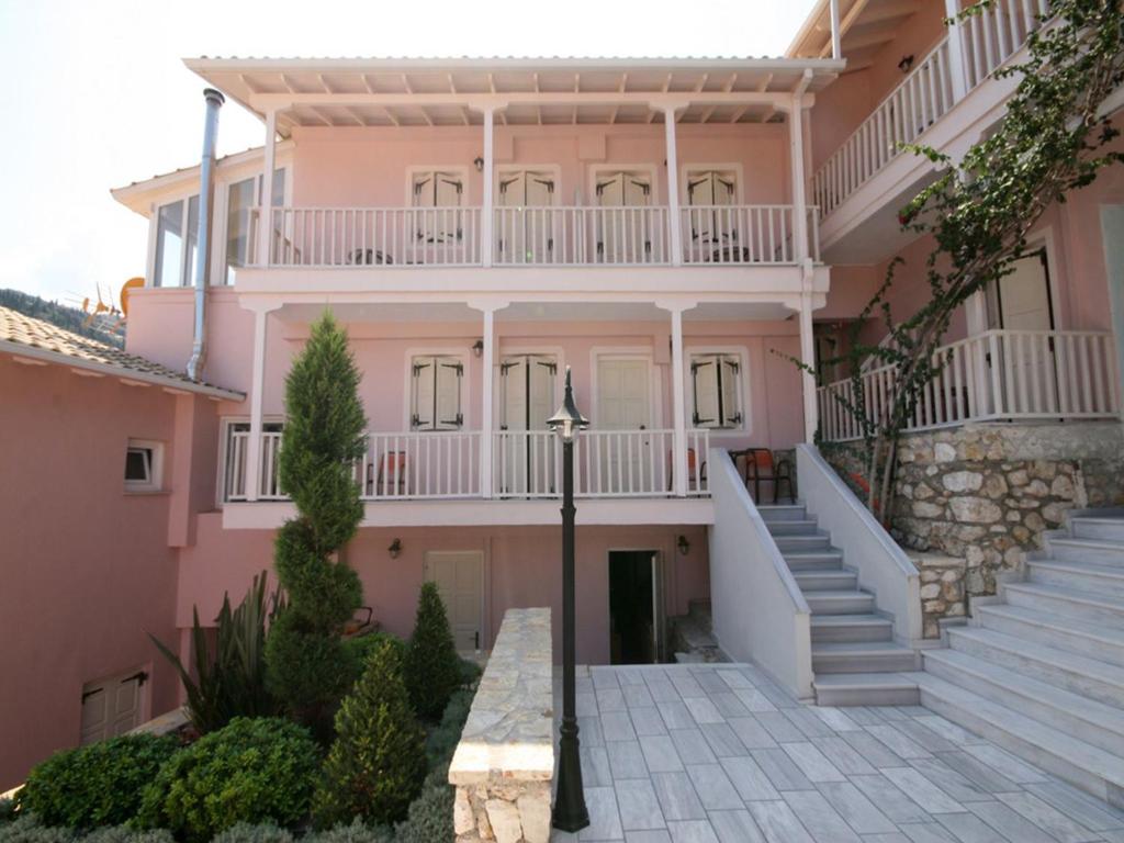 a pink house with stairs and a balcony at Ionis Hotel in Agios Nikitas