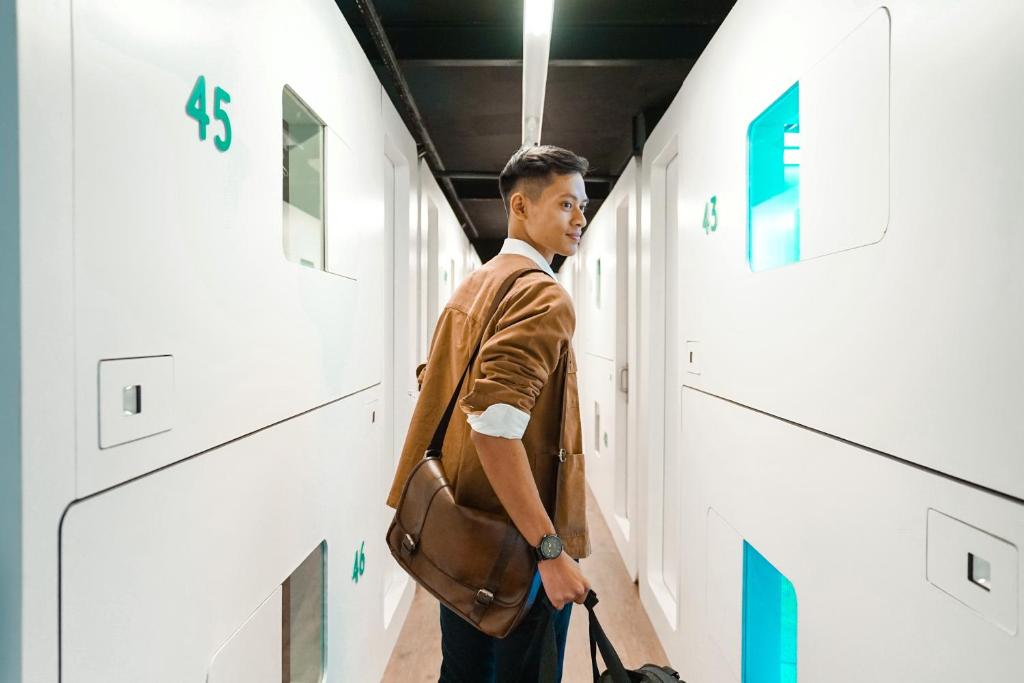 a man standing in a hallway with a bag at Bobopod Alun-Alun, Malang in Bunul