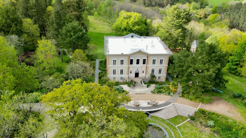 einen Luftblick auf ein großes weißes Haus mit einem Brunnen in der Unterkunft Chateau de Bézyl in Sixt-sur-Aff
