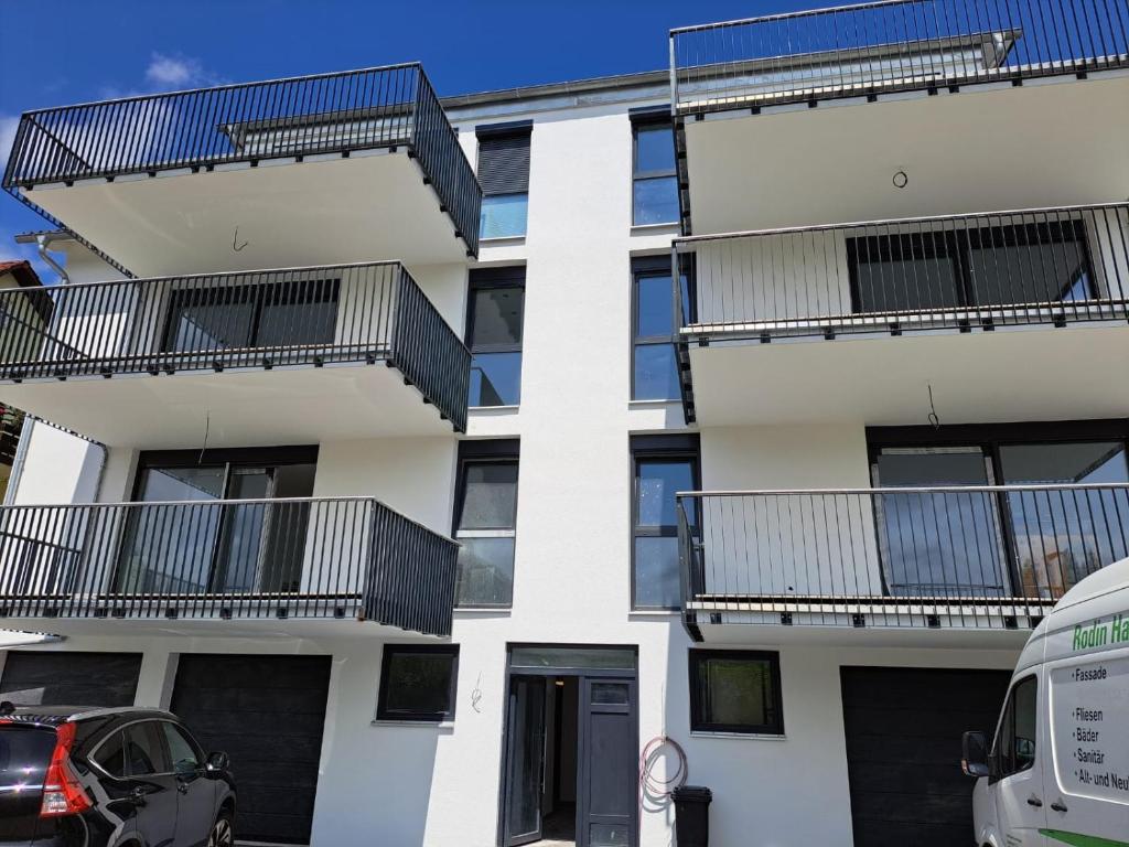 un edificio de apartamentos con balcones y un coche aparcado enfrente en Marko's Wohnung en Rudersberg