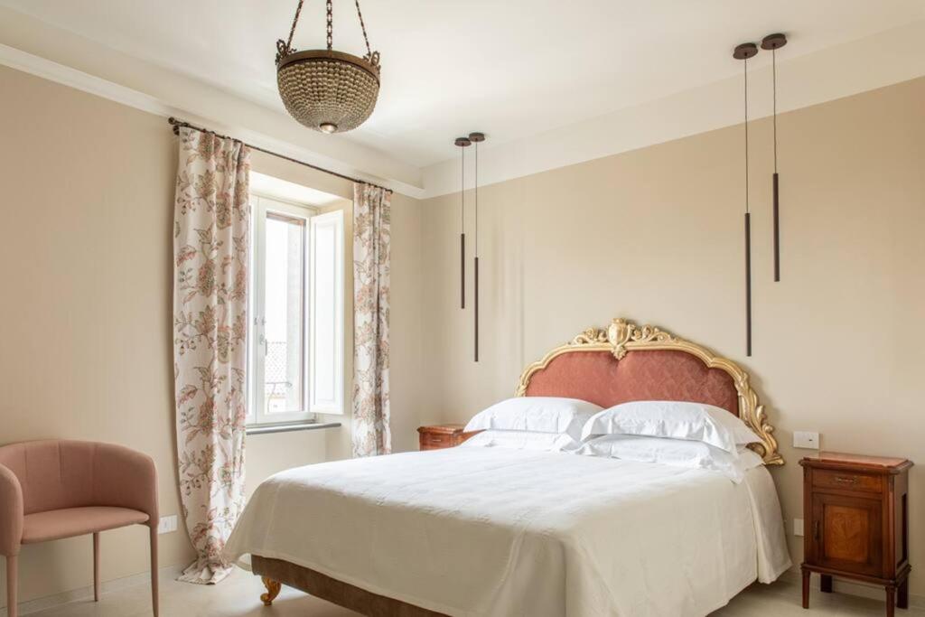 Un dormitorio con una cama y una silla y una ventana. en Palazzo Misciattelli - Ripalta Luxury Residence, en Orvieto