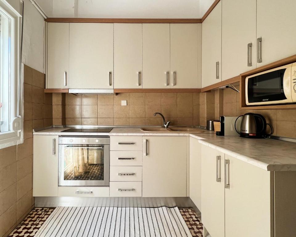 a kitchen with white cabinets and a stove at Nomas Skg Apartment by BiNoBi! in Thessaloniki