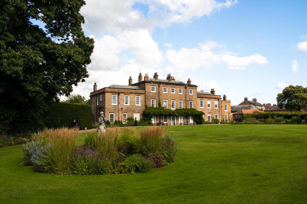 a large brick building in a grassy field at Thirsk Hall South Wing, North Yorkshire in Thirsk