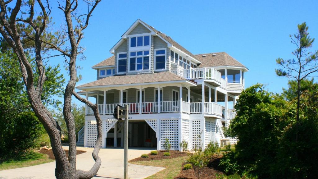 Une grande maison blanche avec balcon est située dans une rue. dans l'établissement Oceanside, Private Pool, Volleyball, Screened porch, PI61, Without a Porpoise, à Corolla