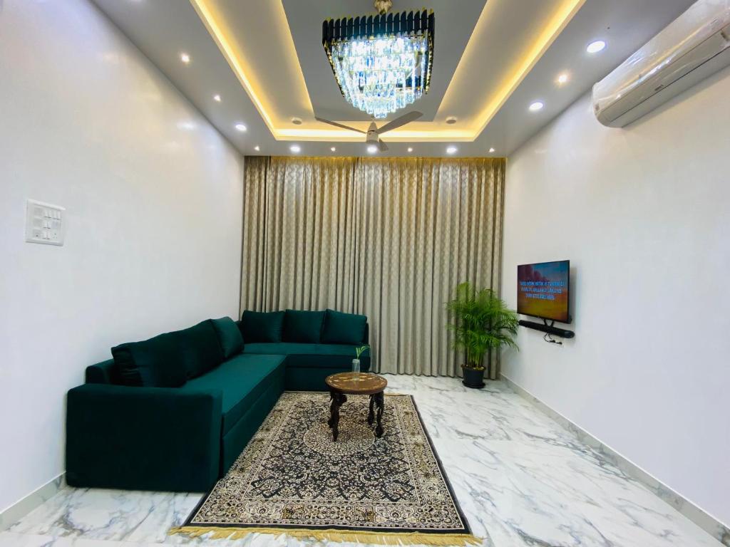 Laxmi Villa 3BHK Premium Villa with terrace Anjuna في أنجونا: غرفة معيشة مع أريكة خضراء وطاولة