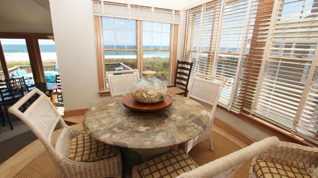 a dining room with a table with chairs and a vase on it at PI76, Life of Reilly- Oceanfront, Ocean Views, Private Pool, Private Beach Access, Foosball in Corolla