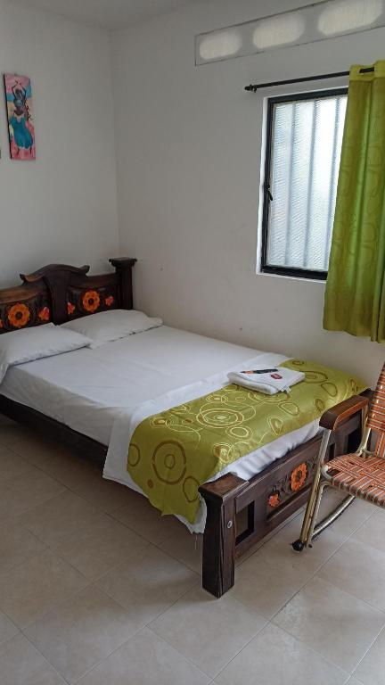 sypialnia z łóżkiem, krzesłem i oknem w obiekcie Hotel El Negro w mieście Mariquita