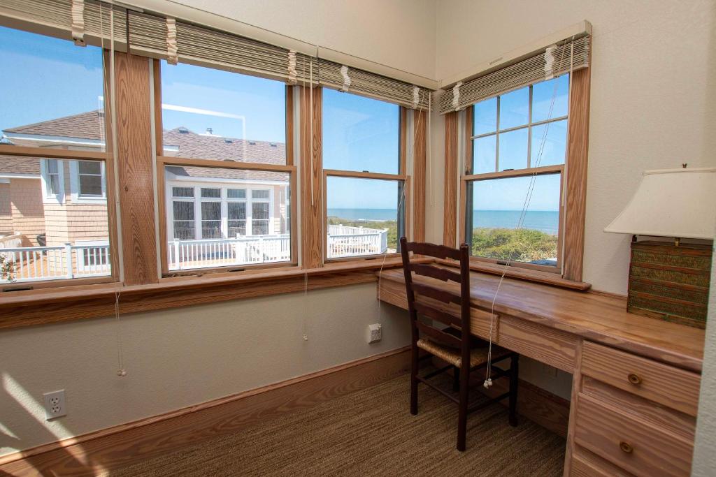 a room with a desk with a chair and windows at PI76, Life of Reilly- Oceanfront, Ocean Views, Private Pool, Private Beach Access, Foosball in Corolla