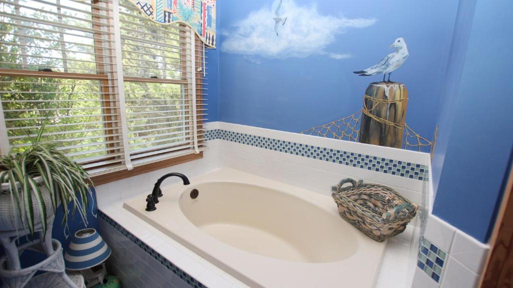 a bathroom with a bath tub with a bird on the wall at PI76, Life of Reilly- Oceanfront, Ocean Views, Private Pool, Private Beach Access, Foosball in Corolla