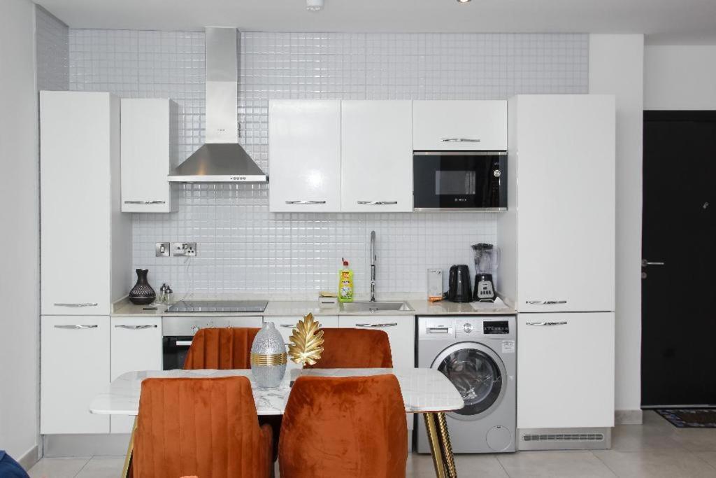 a kitchen with white cabinets and a table with chairs at A307 Luxury 1 Bedroom in Accra