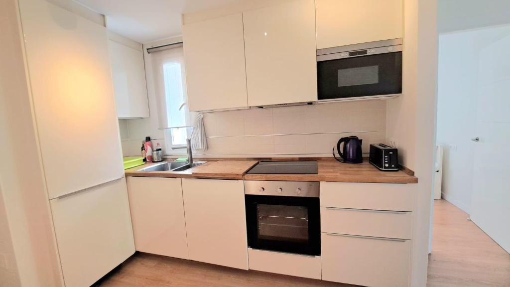 uma cozinha com armários brancos e um forno com placa de fogão em Apartment Las Salinas Boliches em Fuengirola