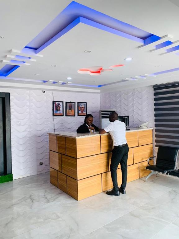 two people standing at a counter in an office at Owee Hotel Apartment and Suites in Lagos
