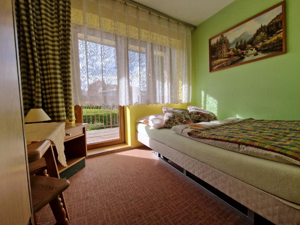 a bedroom with a bed and a large window at Pokoje Gościnne u Lańdy in Poronin