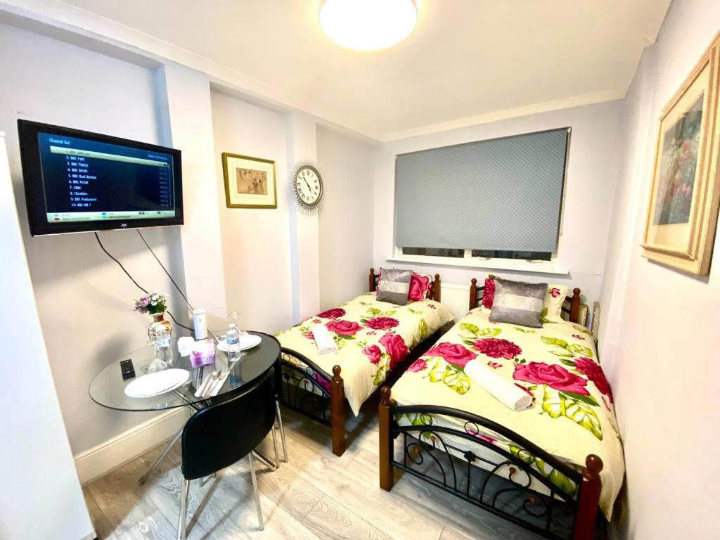 a bedroom with two beds and a table and a tv at Ground Floor One Bed Studio In London in London