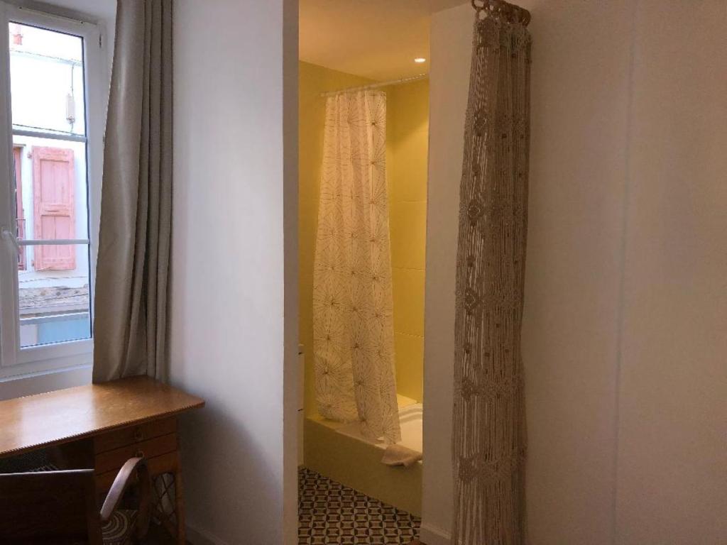 een badkamer met een douchegordijn en een bad bij Seventies, vintage et bohème in Bourgoin
