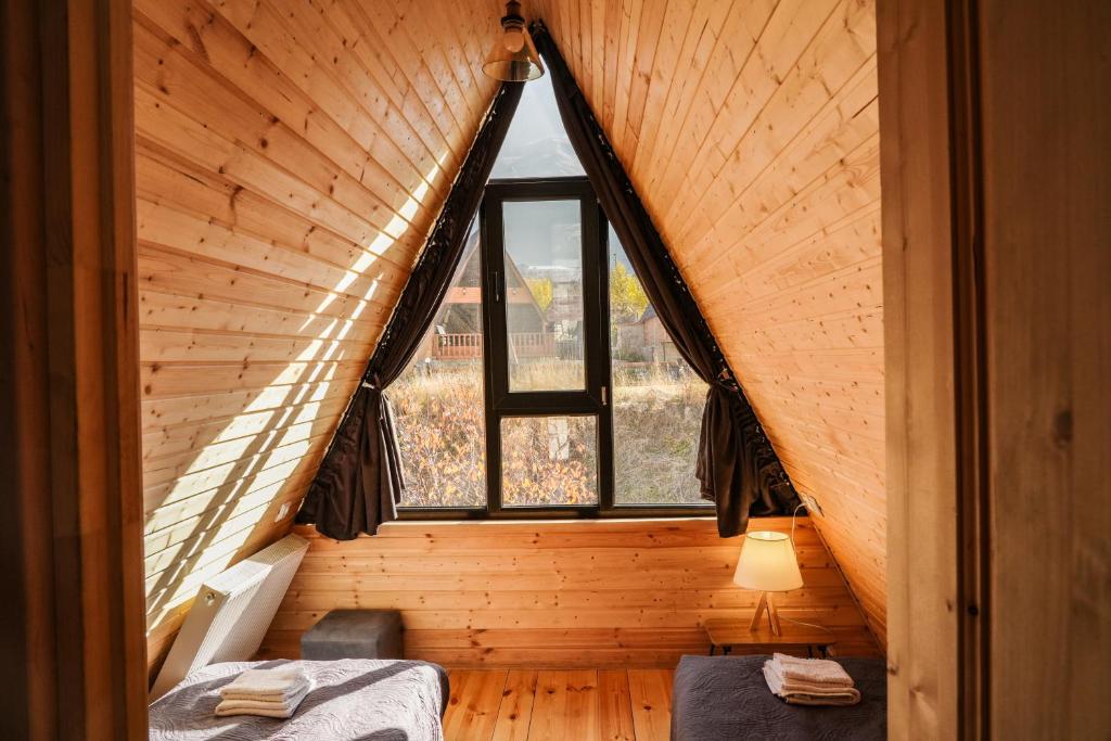 a attic bedroom with a large window in a wooden house at Peak view kazbegi in Kazbegi