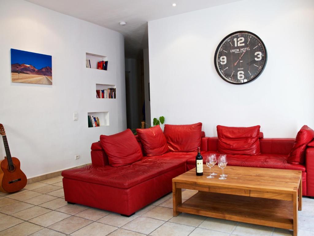 a living room with a red couch and a clock at &quot;Le Zen&quot; in Nice