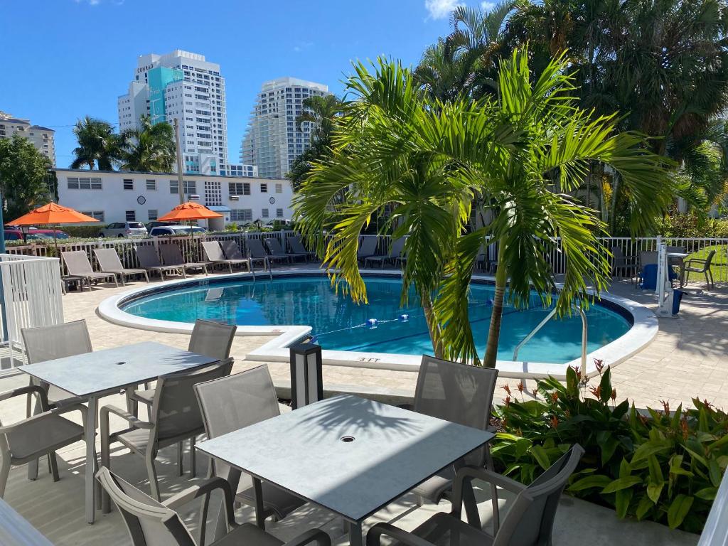 a pool with tables and chairs and a palm tree at Rolo Beach Hotel in Fort Lauderdale