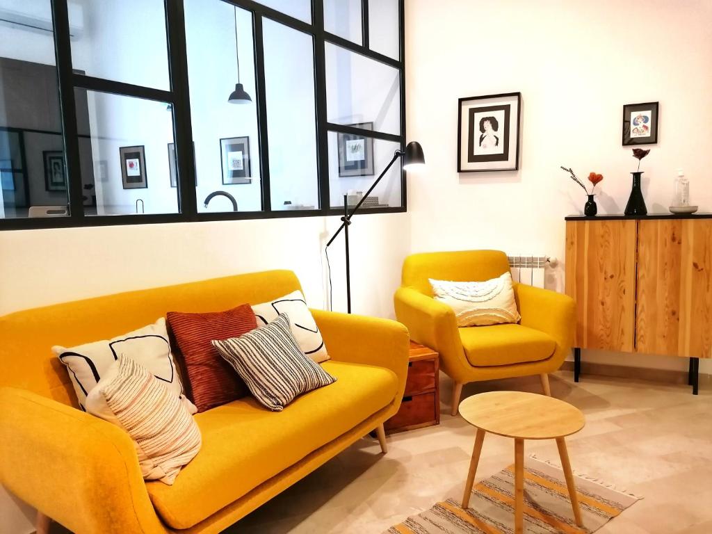 uma sala de estar com um sofá amarelo e uma cadeira em I Canti Comfort Rooms em Palermo