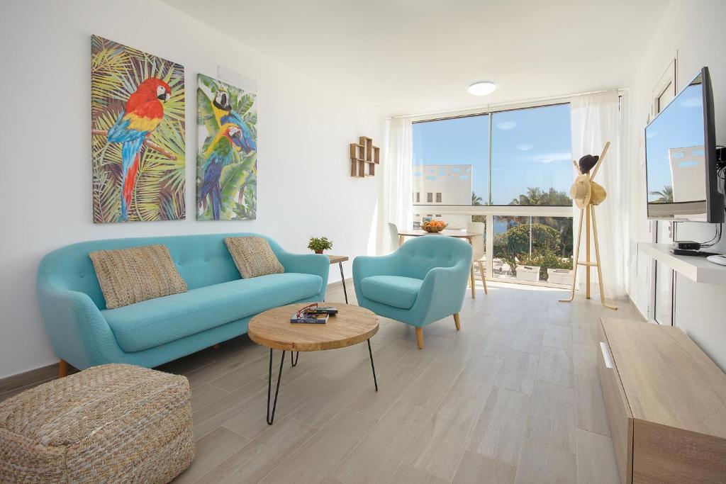 un salon avec un canapé bleu et une table dans l'établissement Red Volcano- pool, gym and activities in Sport Center Fariones included, à Puerto del Carmen