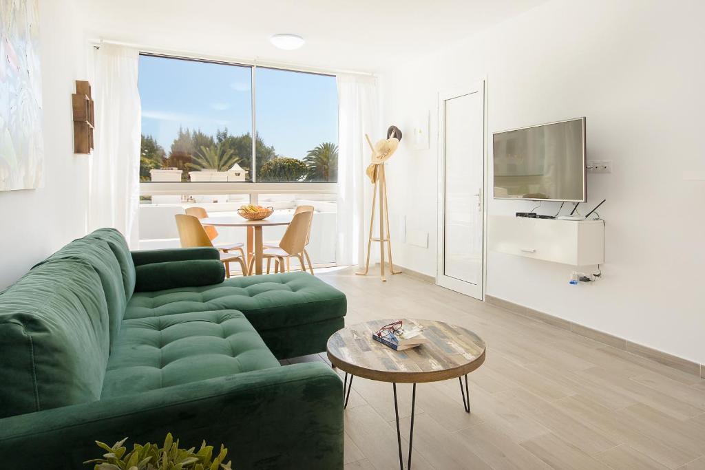 un salon avec un canapé vert et une table dans l'établissement Orange Volcano - pool, gym and activities in Sport Center Fariones included, à Puerto del Carmen