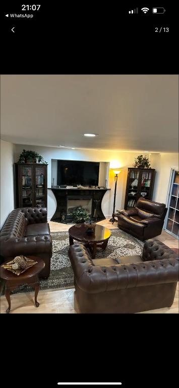 a living room with leather furniture and a flat screen tv at Cozy greenery view among comfort in Haledon