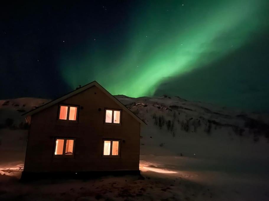 una casa con la aurora en el cielo detrás de ella en Kvaløyvågen Gård AS, en Kvaløya