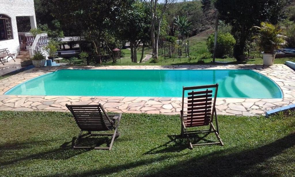 dos sillas sentadas en el césped cerca de una piscina en Lindo Sitio Junto à Natureza en Ibiúna
