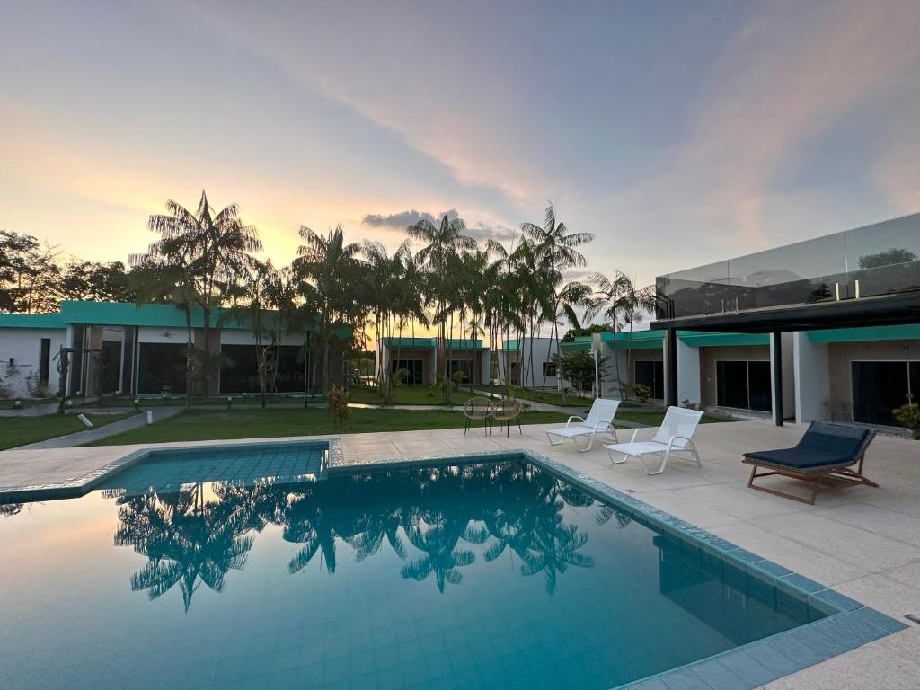 una piscina con 2 sillas y una casa en Villa'S Roraima - Pousada & Natureza en Boa Vista