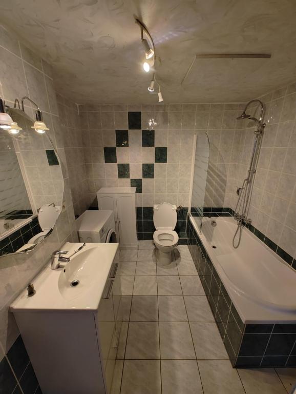 W łazience znajduje się umywalka, toaleta i wanna. w obiekcie Cosy Triplex 3 chambres w mieście Pont-de-lʼArche