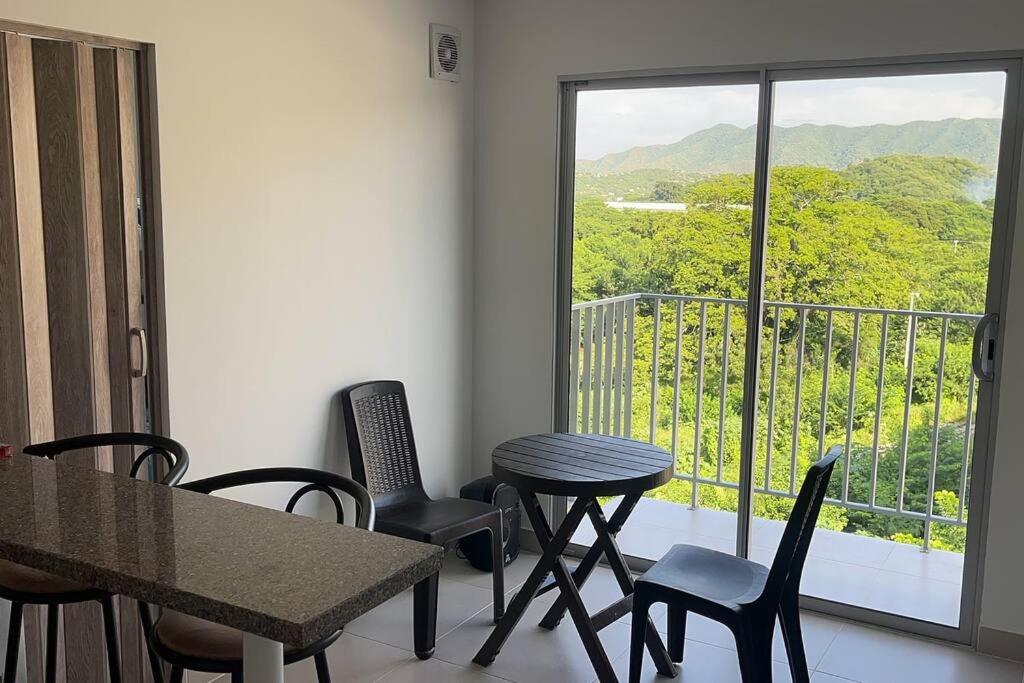 Habitación con mesa, sillas y balcón. en Cómodo alojamiento cerca al Parque Tayrona, en Santa Marta