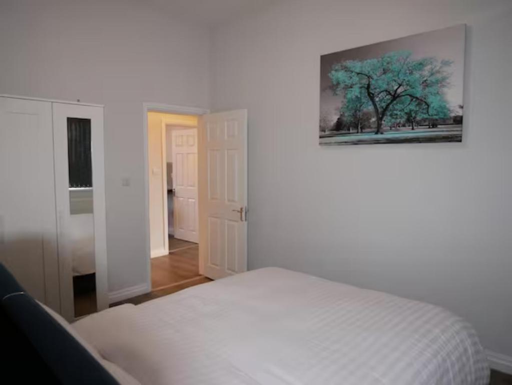 Un dormitorio con una cama blanca y una pintura en la pared en Luxury Living Manchester, en Mánchester