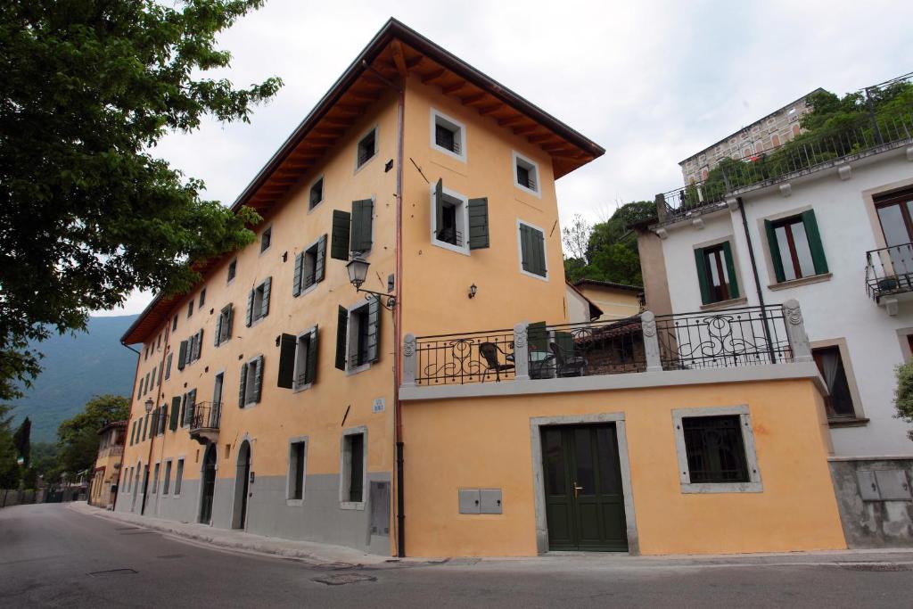 a yellow building with a balcony on a street at Albergo Diffuso Polcenigo P.Lacchin in Polcenigo