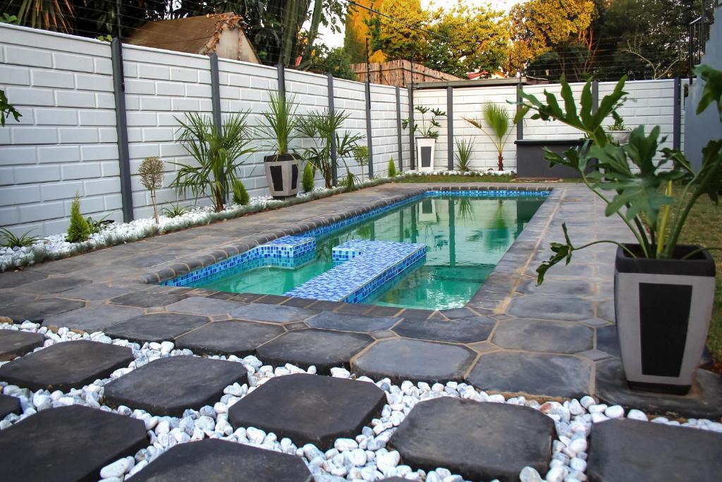 a swimming pool with rocks in a backyard at Villa La Sola B&B and Self-Catering in Boksburg