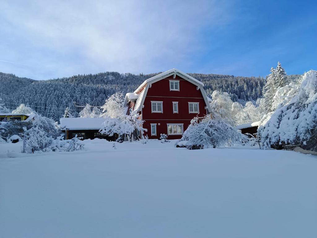 a person standing in front of a red barn with snow at Haus Grünfels ApARTment in Murau