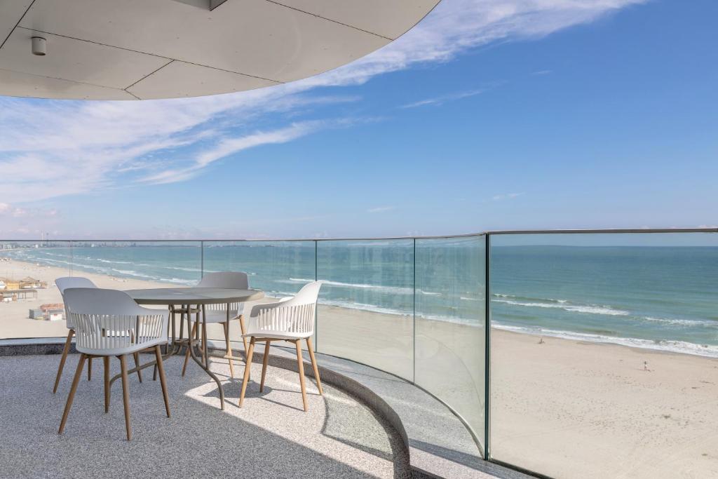 a balcony with a table and chairs and the beach at Sea On Mamaia in Mamaia